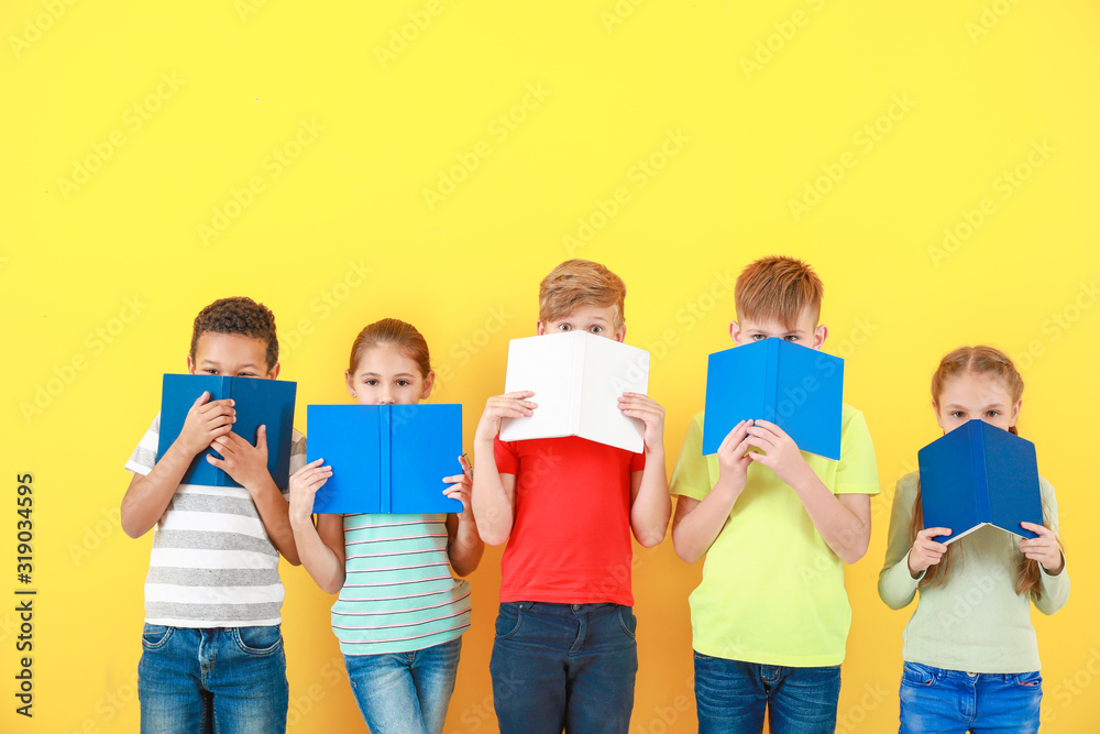 Cute little children with books on color background