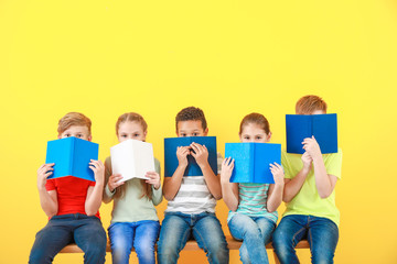 Wall Mural - Cute little children with books on color background