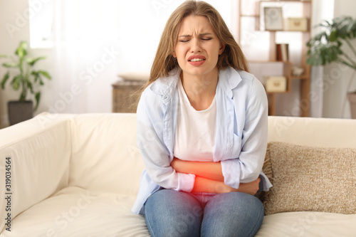 Fotomural Young woman suffering from menstrual cramps at home