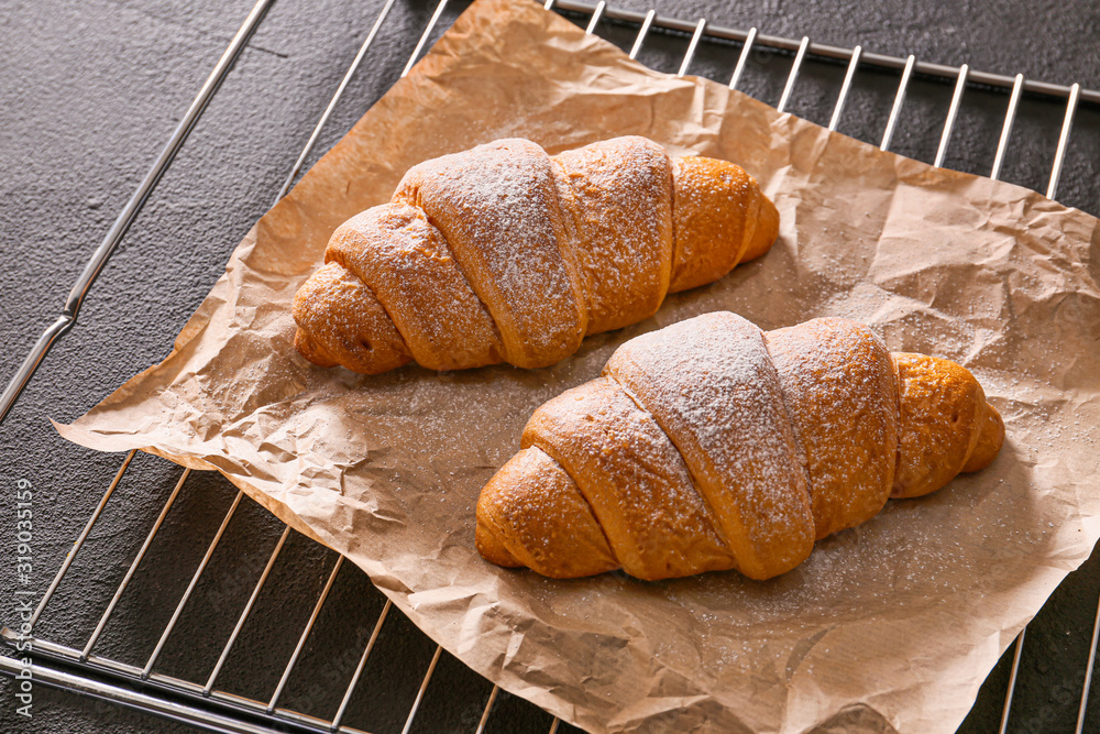 Grid with tasty croissants on dark background
