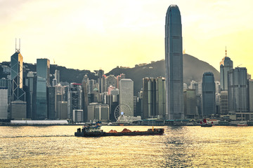 Wall Mural - Dry cargo vessel at Victoria Harbor of Hong Kong at sunset. View from Kowloon on HK Island.