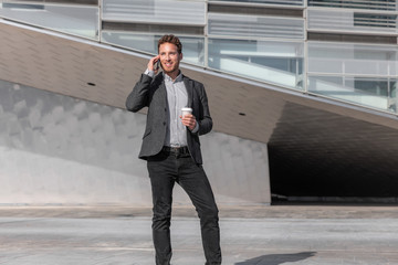 Wall Mural - young business man calling talking on the mobile phone on coffee break from office building outside.