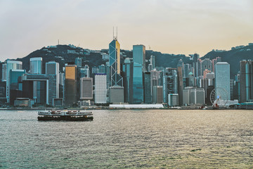 Wall Mural - Star ferry at Victoria Harbor in HK at sunset. View from Kowloon on Hong Kong Island.