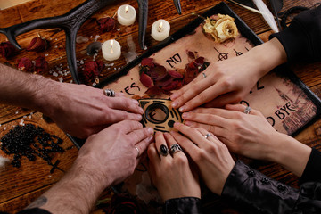 Wall Mural - People conducting a seance using a Ouija Board, or Talking Spirit Board, with white candles. Shot from overhead.