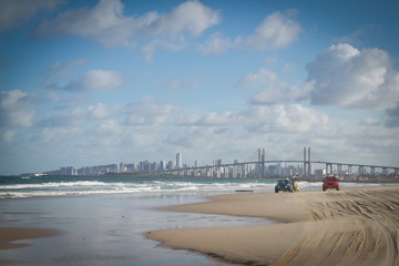 a bridge and city view from the beach sand with lots of tiretrail from buggys and two buggys