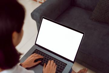 Fototapete - Woman hand using laptop on sofa in house, mock up of blank screen.