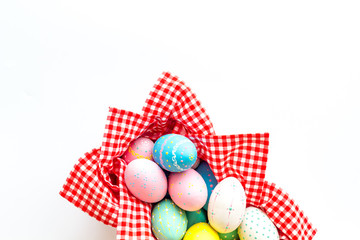 Easter eggs painted in basket on white desk top-down copy space