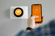 © Saklakova - Man uses a mobile phone with smart home app in modern living room
