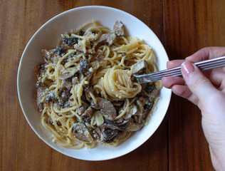 Poster - Mushroom white pasta topped with parmesan on a white plate and on top of a wooden table. 