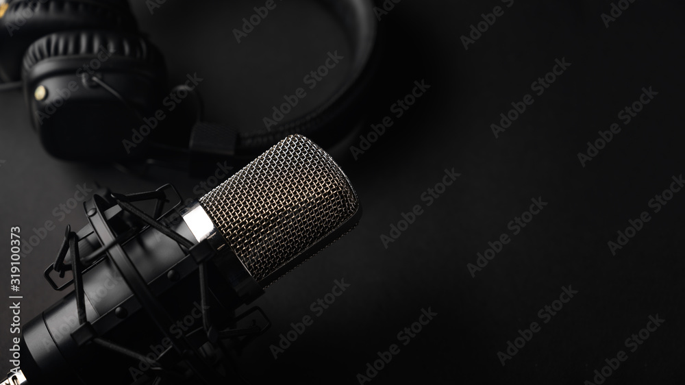 Studio black studio microphone with studio headphones on a black background. Banner. Radio, work with sound, podcasts. - obrazy, fototapety, plakaty 