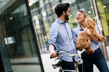 Wall Mural - Laughing young couple with small dog walking in the city