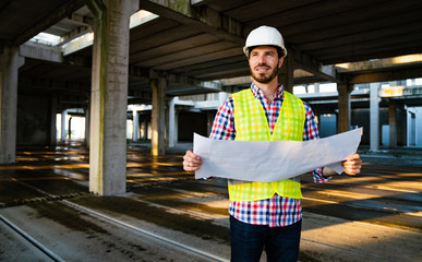 Architect, engineer looking at blueprints in a construction site