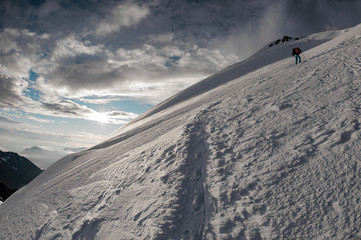 Man with hiking equipment standing on the snow on the mountain hill in far