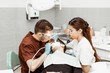 © Natalya Lys - A young male dentist doctor treats a patient. Medical manipulations in dentistry, surgery. Professional uniform and equipment of a dentist. Healthcare Equipping a doctor’s workplace. Dentistry