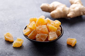 Wall Mural - Candied ginger in black bowl on dark stone background. Close up.