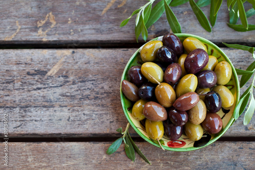 Fotomural Assortment of fresh olives on a plate with olive tree brunches