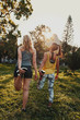 © StratfordProductions - Back view of diverse multiracial female friends stretching their legs in the sunlight at the park