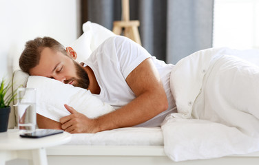 young man sleeping in bed in bedroom in morning.