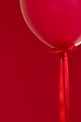 Wall Mural - red helium balloon with a red ribbon on red background