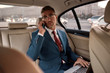 © Svitlana - Being good in business. Confident and stylish mature businessman in full suit working on his laptop and talking on the phone with business partner while sitting in the car