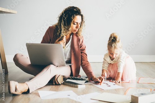 Fotografía Businesswoman working on laptop while coloring with daughter