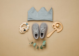 Wall Mural - Knitted crown, wooden toys and shoes on beige background