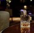 Crystal whisky glass on round wooden table in luxury lounge
