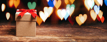  Gift Box On Wooden Table With Shiny Heart Shaped Lights.