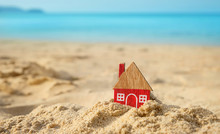 Red House On Sand Beach Background. Creative Concept Of Mortgage, Real Estate. Eco Friendly House. Home, Symbol Of Love, Family. Concept Of Protecting Home.  Copy Space