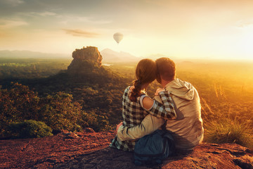 couple of travelers watch a beautiful sunset near the famous rocky plateau Lion peak, Sigiriya. Sri Lanka