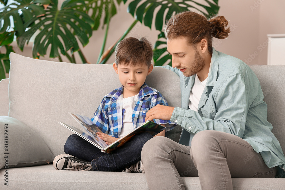 Father and his little son reading book at home