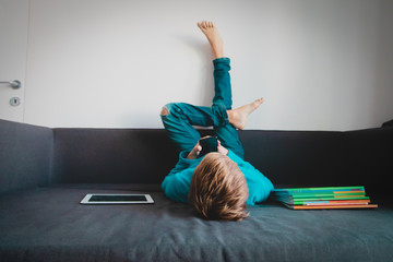 Wall Mural - boy relaxed and looking at mobile phone, kid with touch pad and books