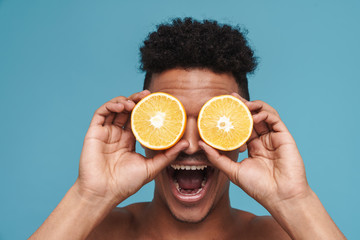 Wall Mural - Photo of shirtless african american man making fun with orange