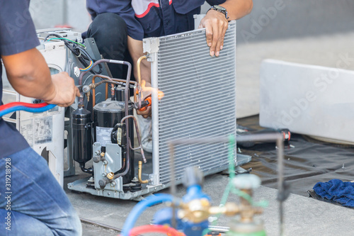 Close up of Air Conditioning Repair team use fuel gases and oxygen to weld or cut metals, Oxy-fuel welding and oxy-fuel cutting processes, repairman on the floor fixing air conditioning system