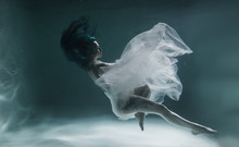 A Beautiful Girl With Blue And Long Hair Swims Underwater In The Pool In A Fluffy White Dress. Looks Like A Nymph Or A Mermaid