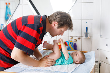 Loving father changing diaper of his newborn baby daughter.