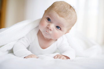 Wall Mural - Baby girl wearing white towel or winter overal in white sunny bedroom