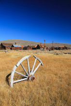 Old Wooden Wheel Lying Lonely In The Dry Grass Near The Abandoned Gold Mining Town Bodie In California. USA