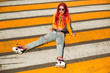Bright exciting girl with red hair, 90s, 2000s style, T-shirt, wide jeans, bananas, sneakers. Sitting at a pedestrian crossing