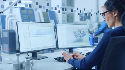 Poster - Industrial Female Engineer Working on a Personal Computer, Two Monitor Screens Show CAD Software with 3D Prototype of New Hybrid Hydrogen Engine and Charts. Modern Factory with High-Tech Machinery