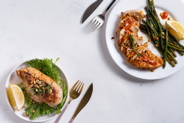 Wall Mural - Grilled chicken breast with grilled asparagus and lemon slice on stone background . Paleo diet.