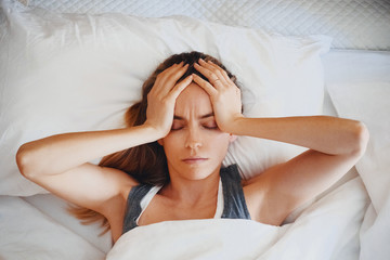 Beauty, young woman with headache on bed