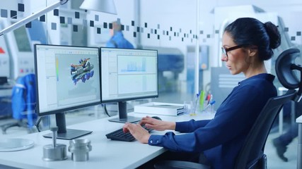 Poster - Female Industrial Engineer Solving Problems, Working on a Personal Computer, Two Monitor Screens Show CAD Software with 3D Prototype of Zero-Emissions Engine Being Tested. Working Modern Factory