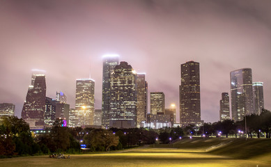 Wall Mural - Houston Texas city skyline and green field park on a cloudy foggy evening	