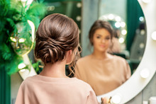 Back View Of Pretty Brunette Young Woman With Hairstyle In Front Of The Mirror At Beauty Salon.