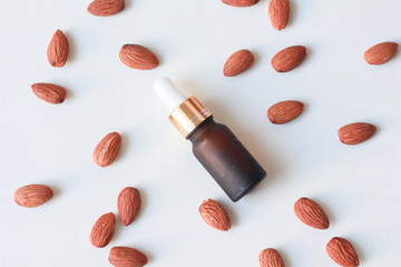 Dropper glass bottle almonds essential oil with almond seeds on white background. Top view.