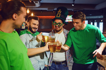 Wall Mural - Happy friends with beer in their hands St. Patrick's Day in a bar.