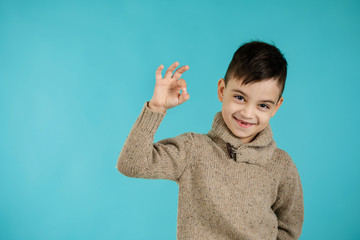 cute little boy in t-shirt making Ok gesture on blue background.