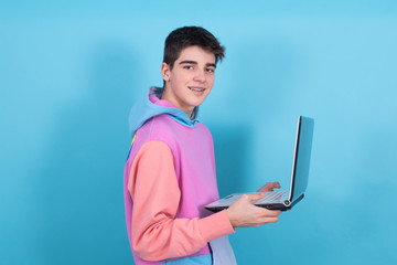 Wall Mural - young teenage man or student with laptop isolated on blue background