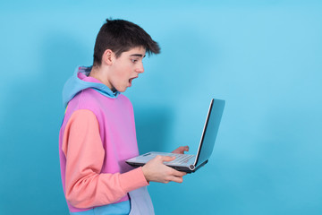 Wall Mural - young teenage man or student with laptop isolated on background with surprise or success expression